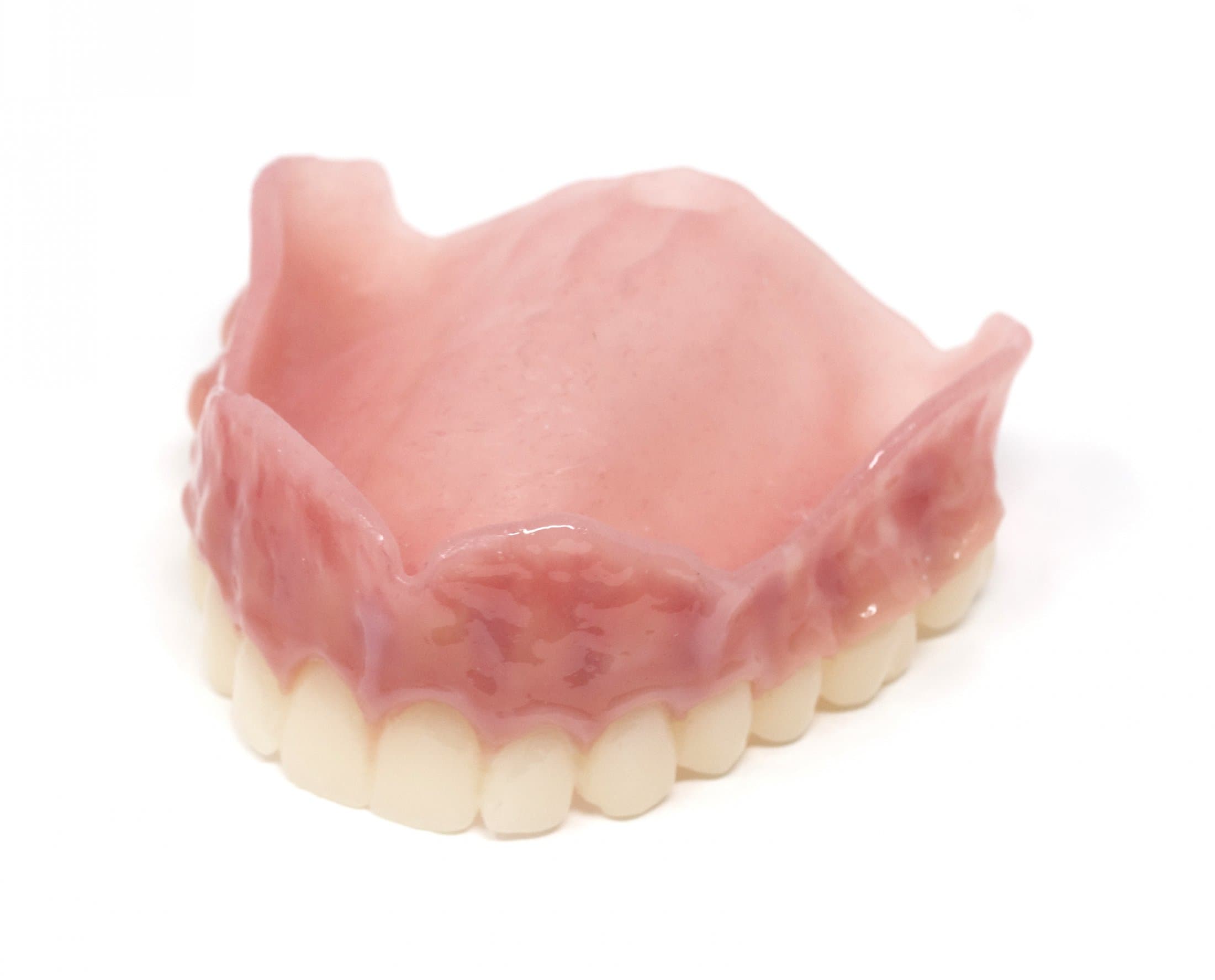 Upper denture with white teeth and a pink gum base on a white background