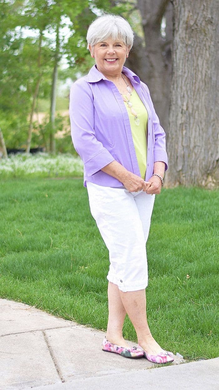 White-haired grandmother wearing a lavender shirt and white cropped trousers